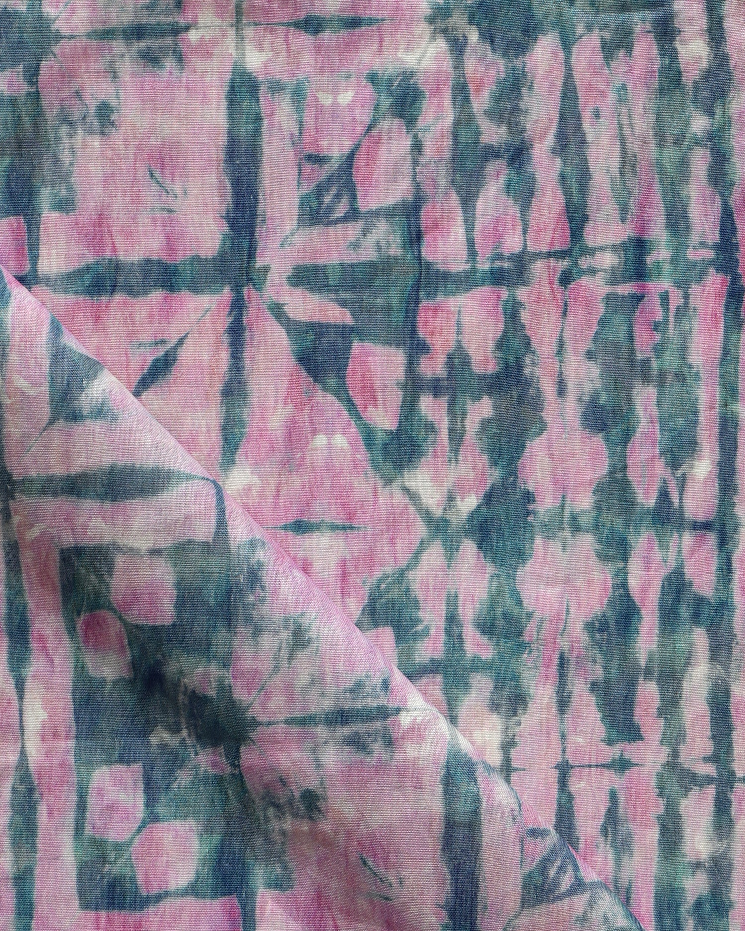 Detail of draped fabric in a watercolor dyed grid print in mottled pink and navy.