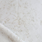 Detail of draped fabric in a painterly bandana print in beige on a cream field.