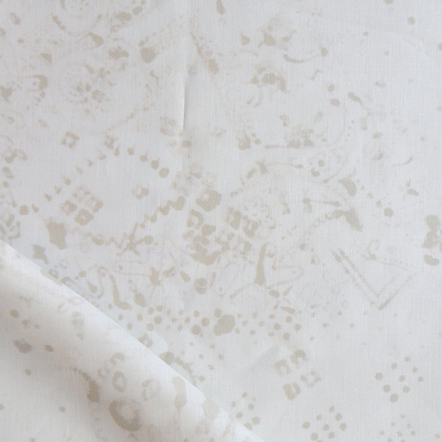 Detail of draped fabric in a painterly bandana print in beige on a cream field.