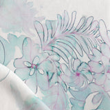 Detail of draped fabric in a painterly floral print in shades of green and purple on a white field.