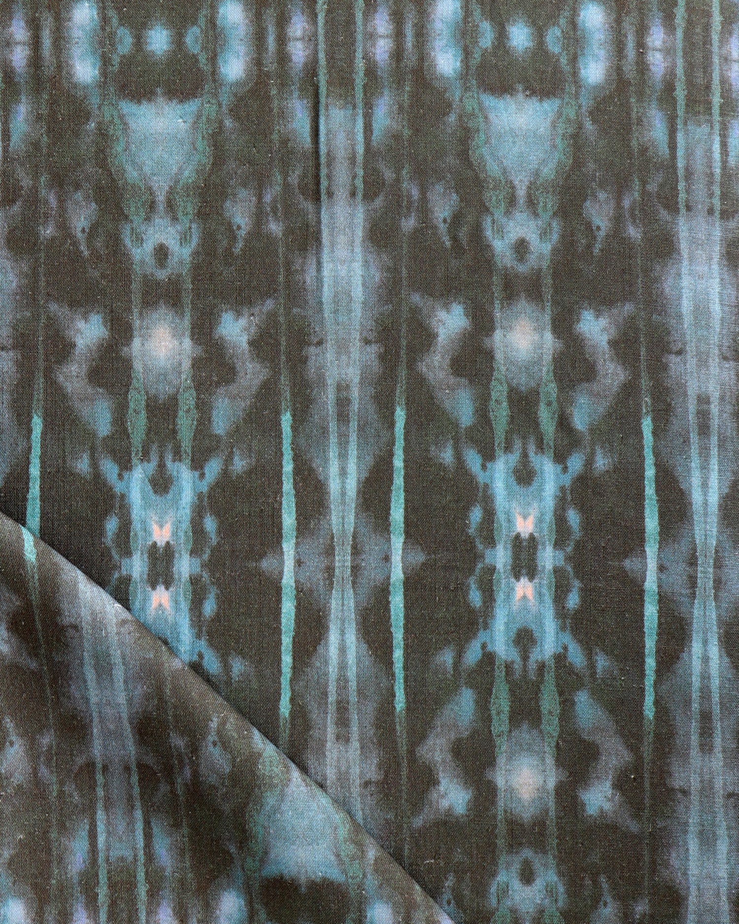 Detail of draped fabric in a painterly ikat print in turquoise and brown.