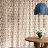 Floor length curtain in watercolor brown pattern with a wooden table with flowers and blue pendant lamp. 