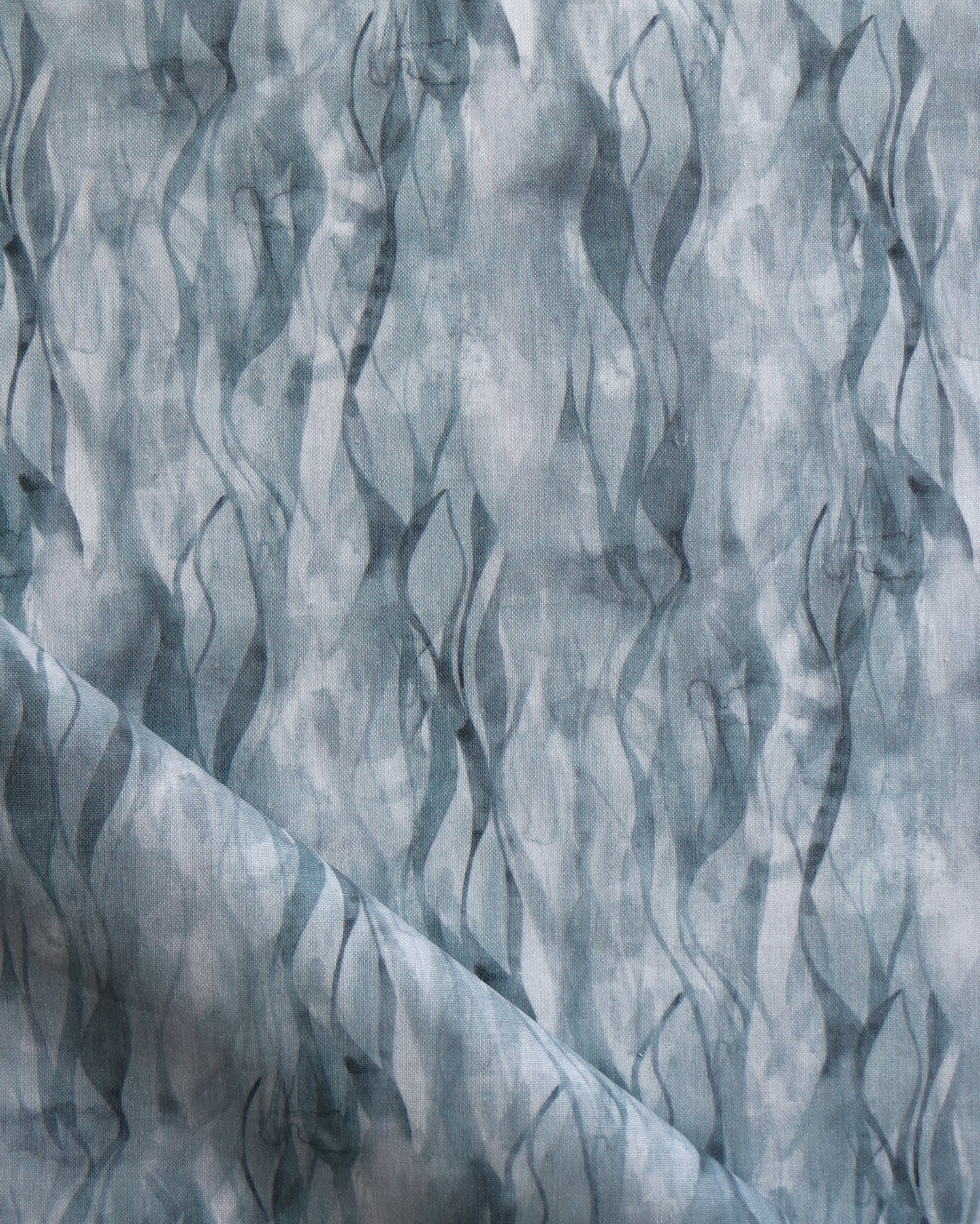 Draped fabric in a layered squiggle watercolor pattern in shades of steel blue. 