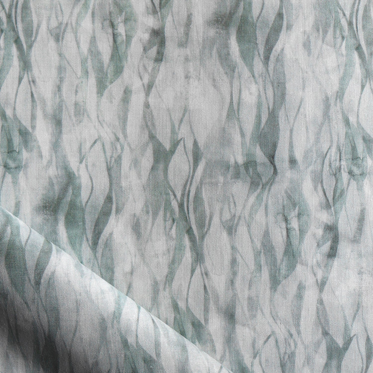 Draped fabric in a layered squiggle watercolor pattern in shades of muted teal. 