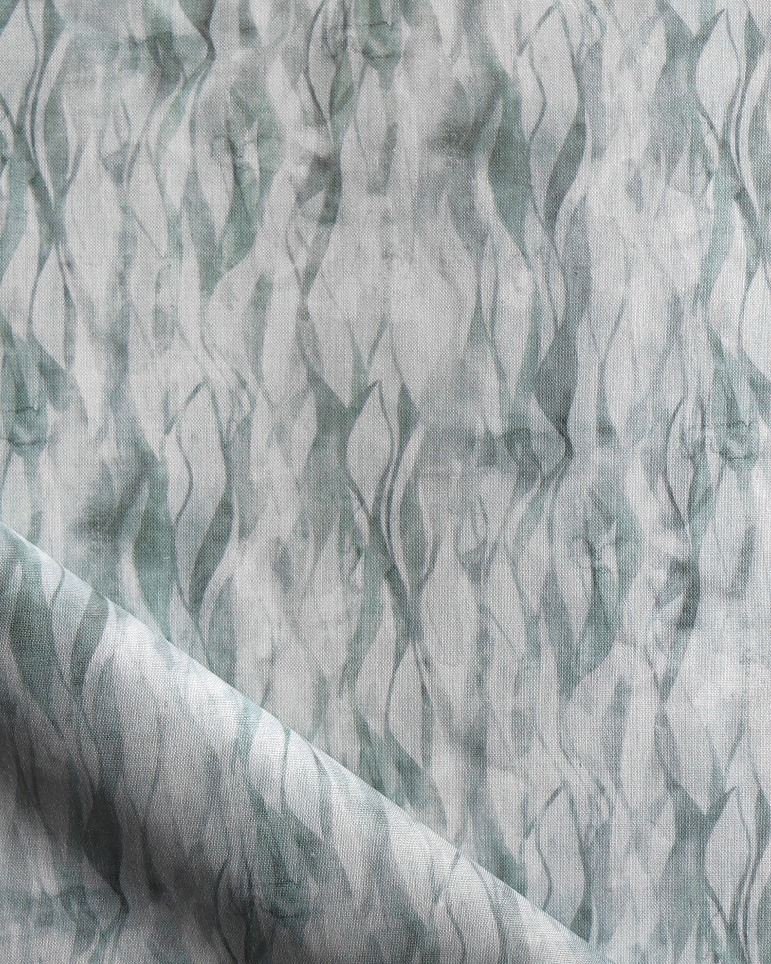 Draped fabric in a layered squiggle watercolor pattern in shades of muted teal. 