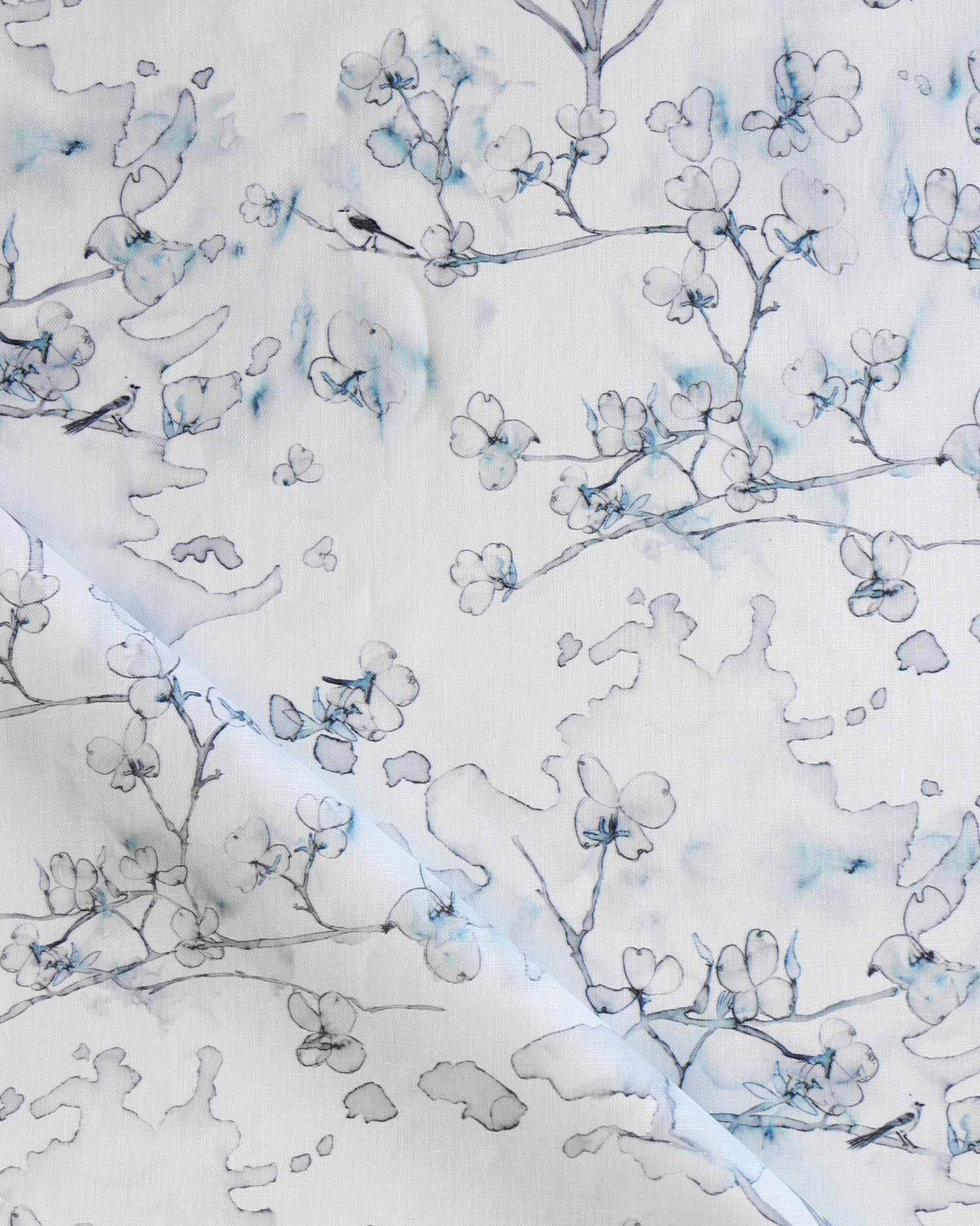 Draped fabric in a watercolor branch and floral pattern in shades of blue on a white field.