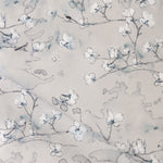 Draped fabric in a watercolor branch and floral pattern in grey and blue on a taupe muted taupe field. 