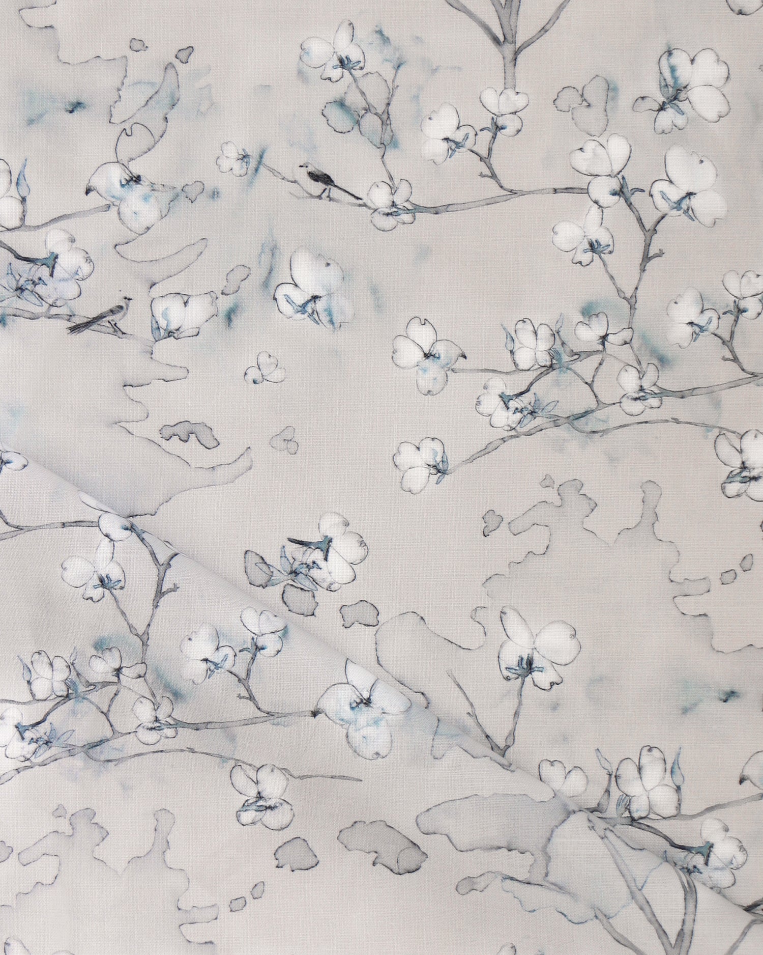 Draped fabric in a watercolor branch and floral pattern in grey and blue on a taupe muted taupe field. 