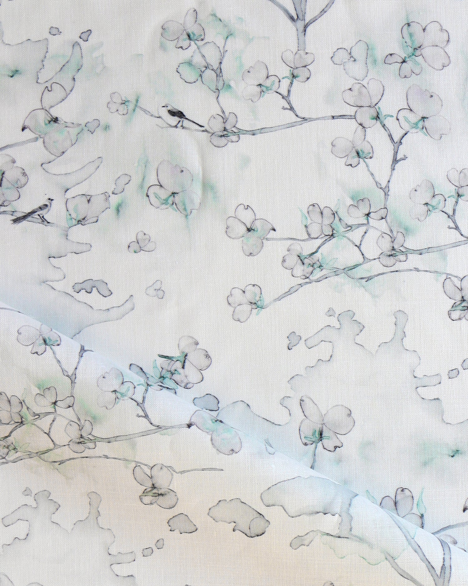 Draped fabric in a watercolor branch and floral pattern in teal green on a white field.