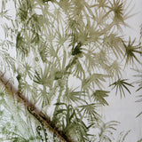 Detail of draped fabric in a painterly palm tree print in olive on a cream field.