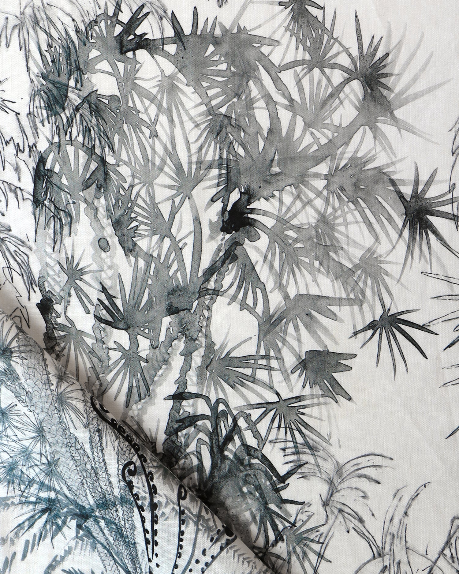Detail of draped fabric in a painterly palm tree print in gray on a cream field.