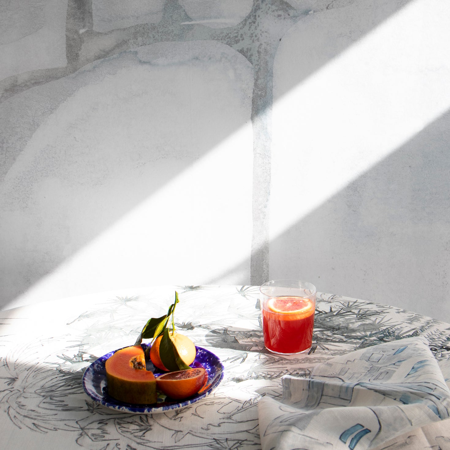 Dining room scene with a table cloth in a painterly palm tree print in gray on a cream field.