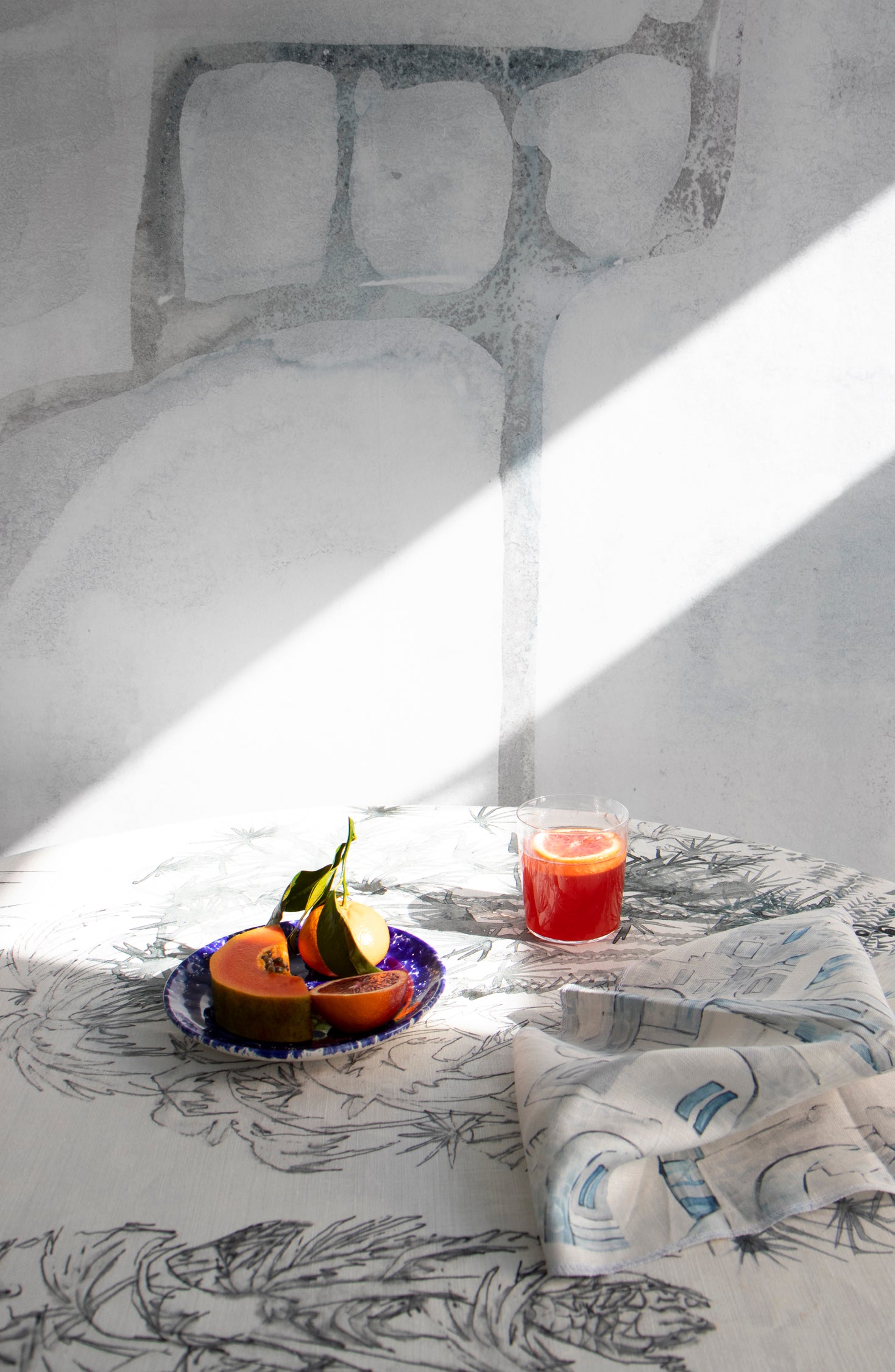 Dining room scene with a table cloth in a painterly palm tree print in gray on a cream field.