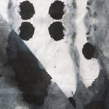 Detail of draped fabric in a watercolor ink blot print in shades of charcoal and gray on a white field.