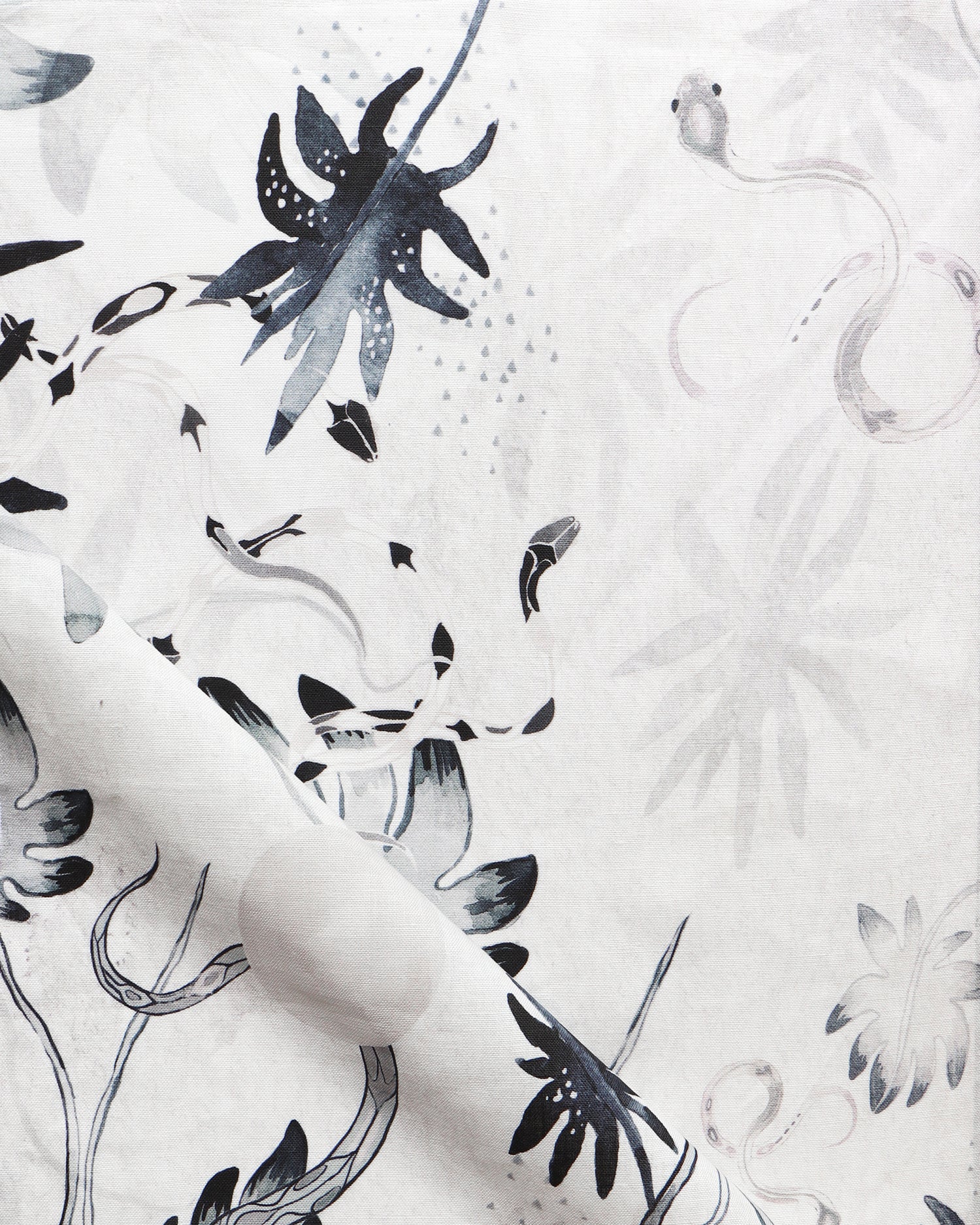 Detail of draped fabric in a playful leaf and snake print in gray and navy on a cream field.
