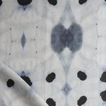 Detail of draped fabric in a watercolor ink blot print in shades of charcoal and black on a greige field.
