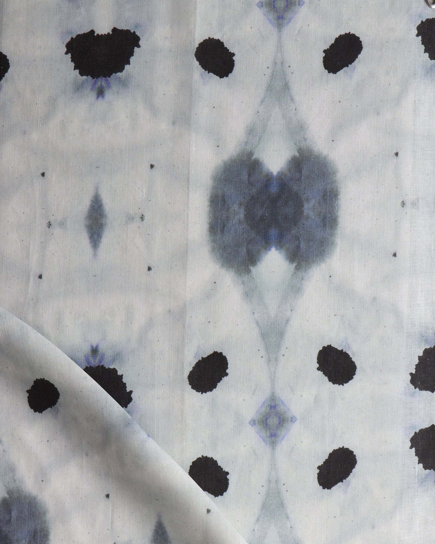 Detail of draped fabric in a watercolor ink blot print in shades of charcoal and black on a greige field.