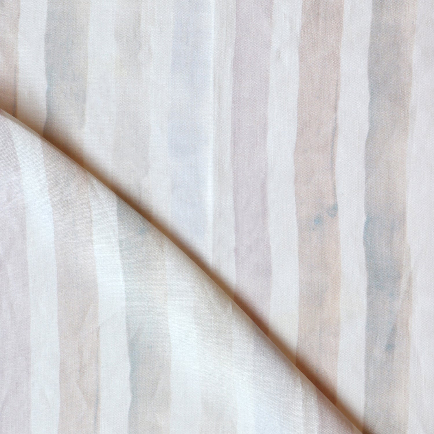 Detail of draped fabric in a painterly stripe print in shades of pink, gray and cream on a white field.
