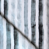 Detail of draped fabric in a painterly stripe print in shades of gray on a white field.