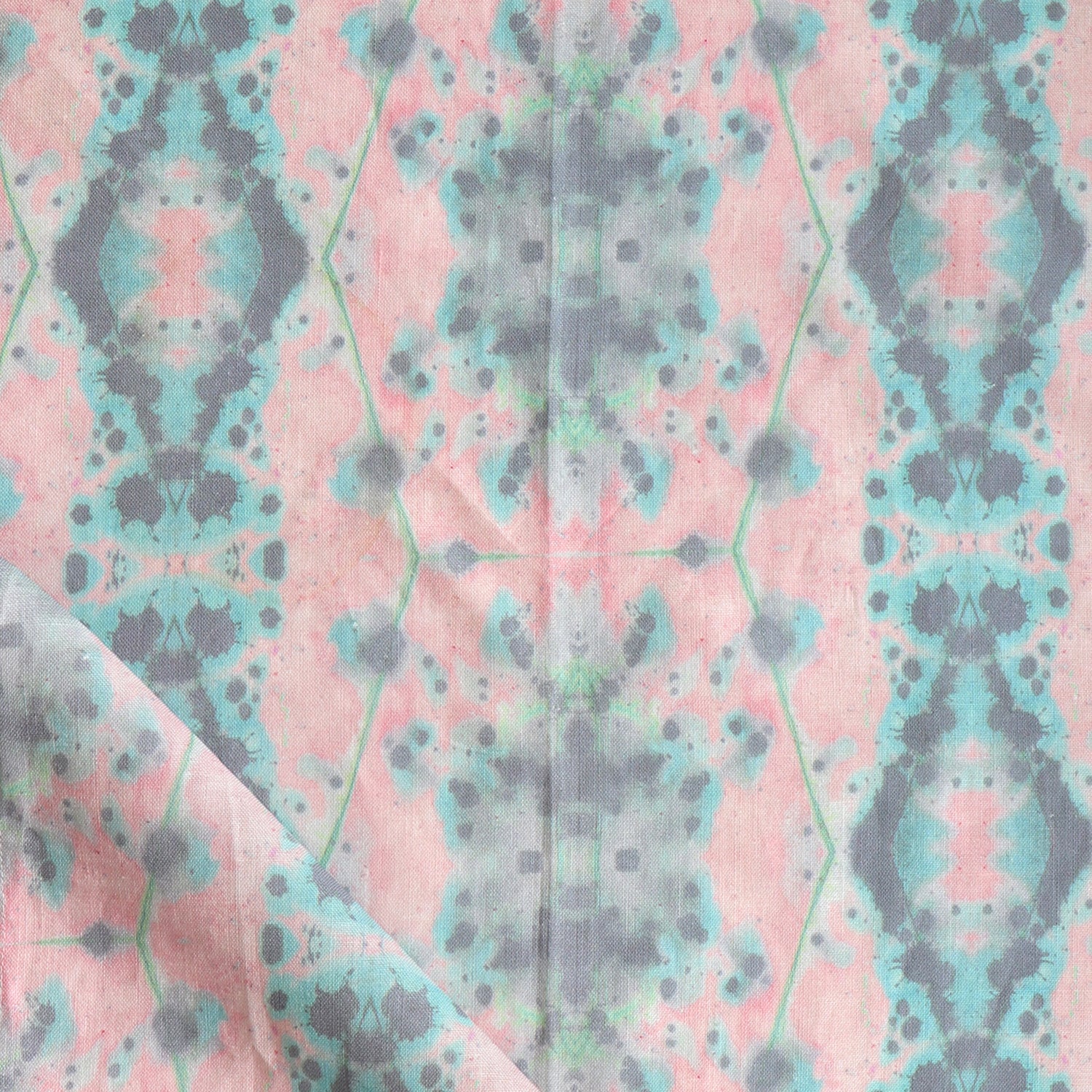 Detail of draped fabric in a painterly gometric stripe in gray, blue and green on a pink field.