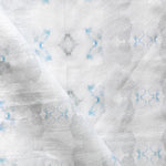 Detail of draped fabric in a striped ink blot print in shades of gray and blue on a cream field.