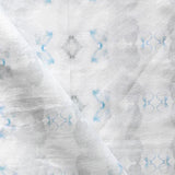 Detail of draped fabric in a striped ink blot print in shades of gray and blue on a cream field.