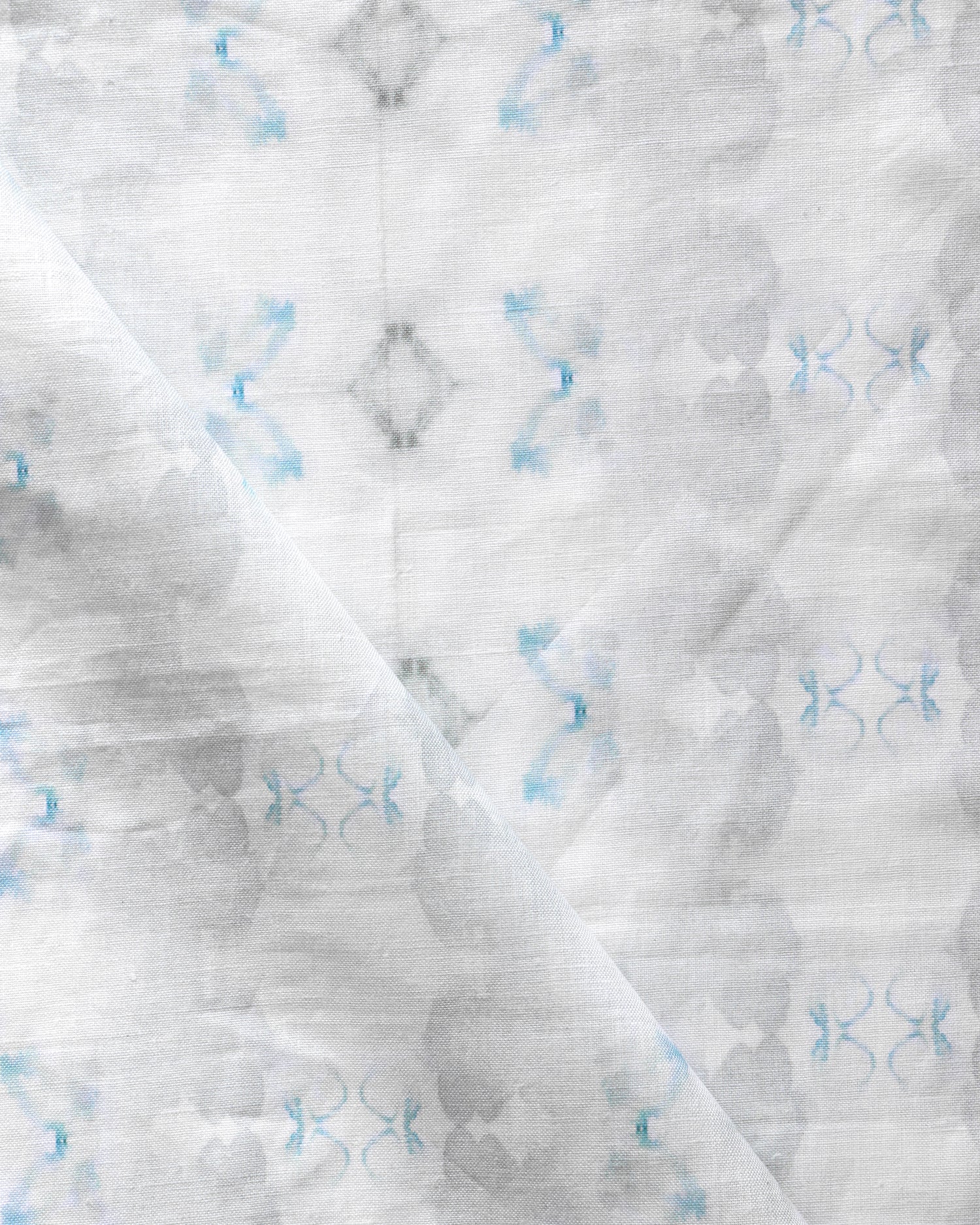 Detail of draped fabric in a striped ink blot print in shades of gray and blue on a cream field.