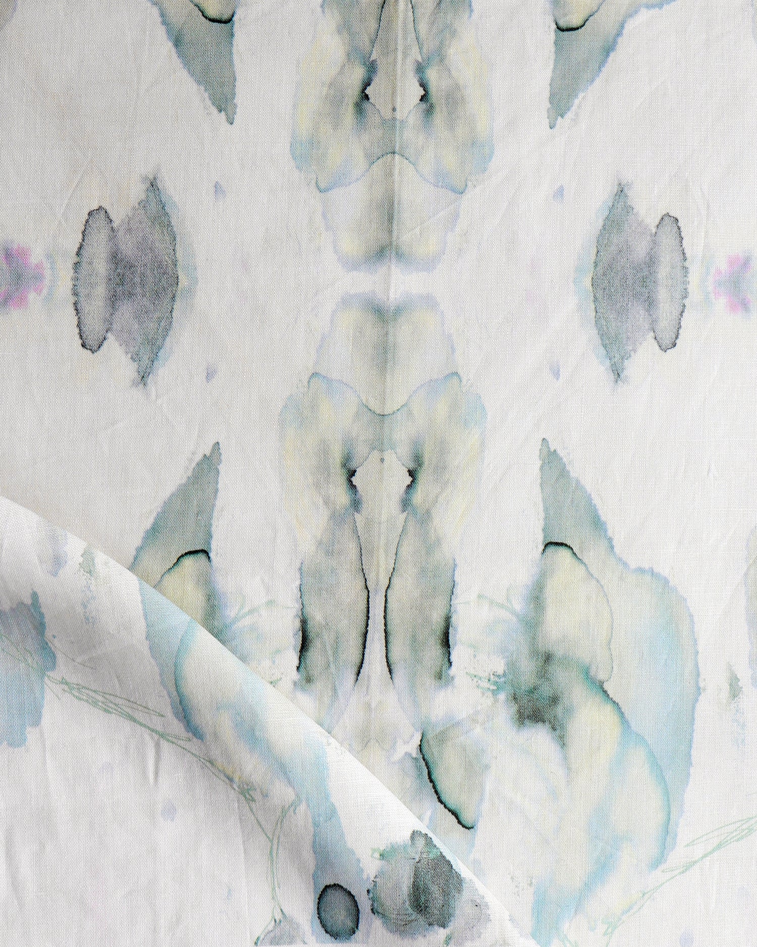 Detail of draped fabric in a watercolor paint blotch print in shades of gray and blue on a white field.