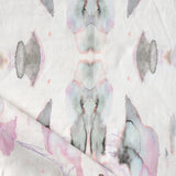 Detail of draped fabric in a watercolor paint blotch print in shades of gray and pink on a white field.