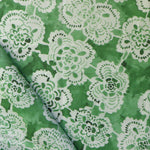 Green fabric with white lace-like floral patterns