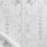 Detail of draped fabric in a watercolor ink blot print in gray on a white field.