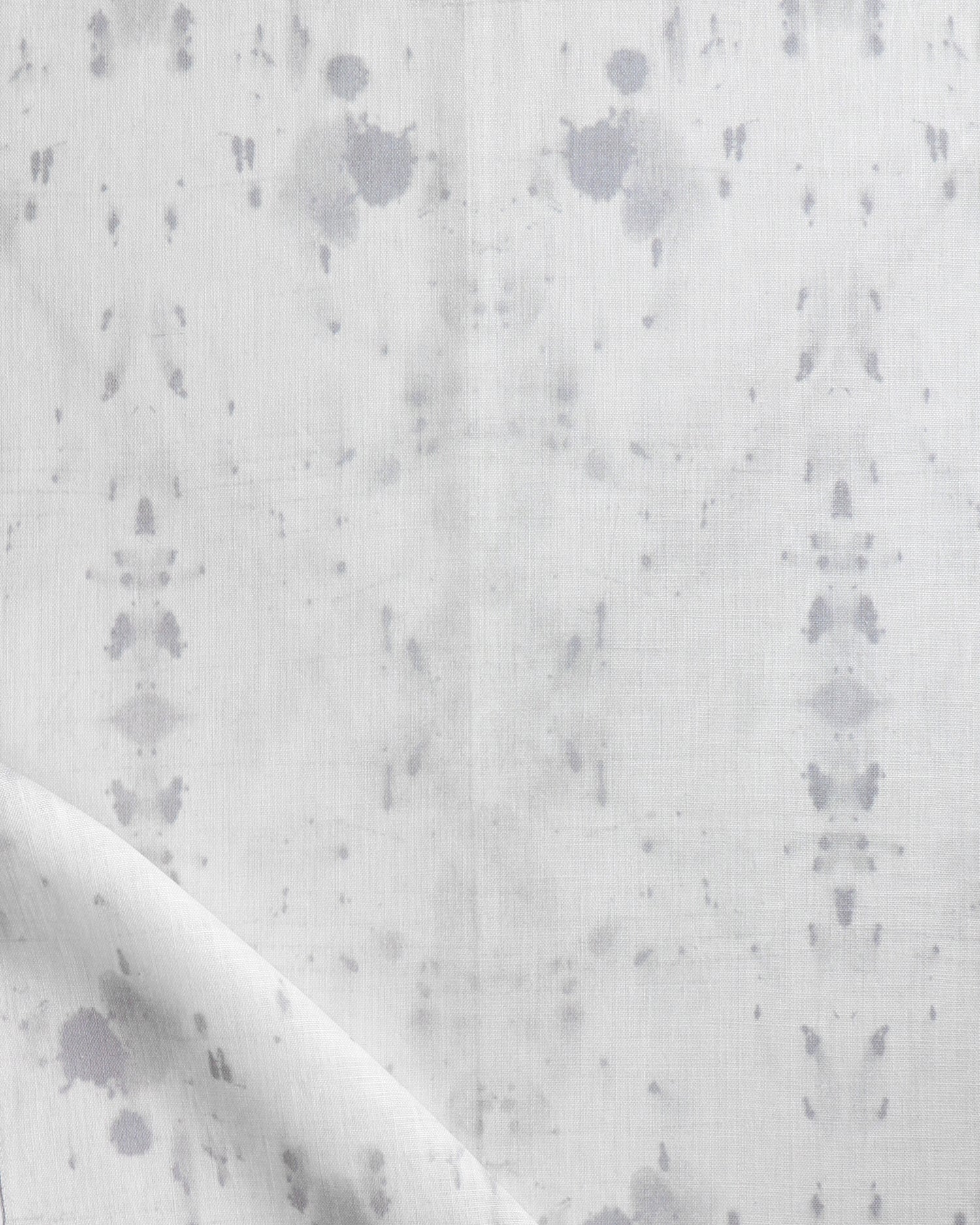 Detail of draped fabric in a watercolor ink blot print in gray on a white field.