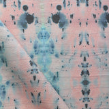 Detail of draped fabric in a watercolor ink blot print in blue and gray on a light pink field.