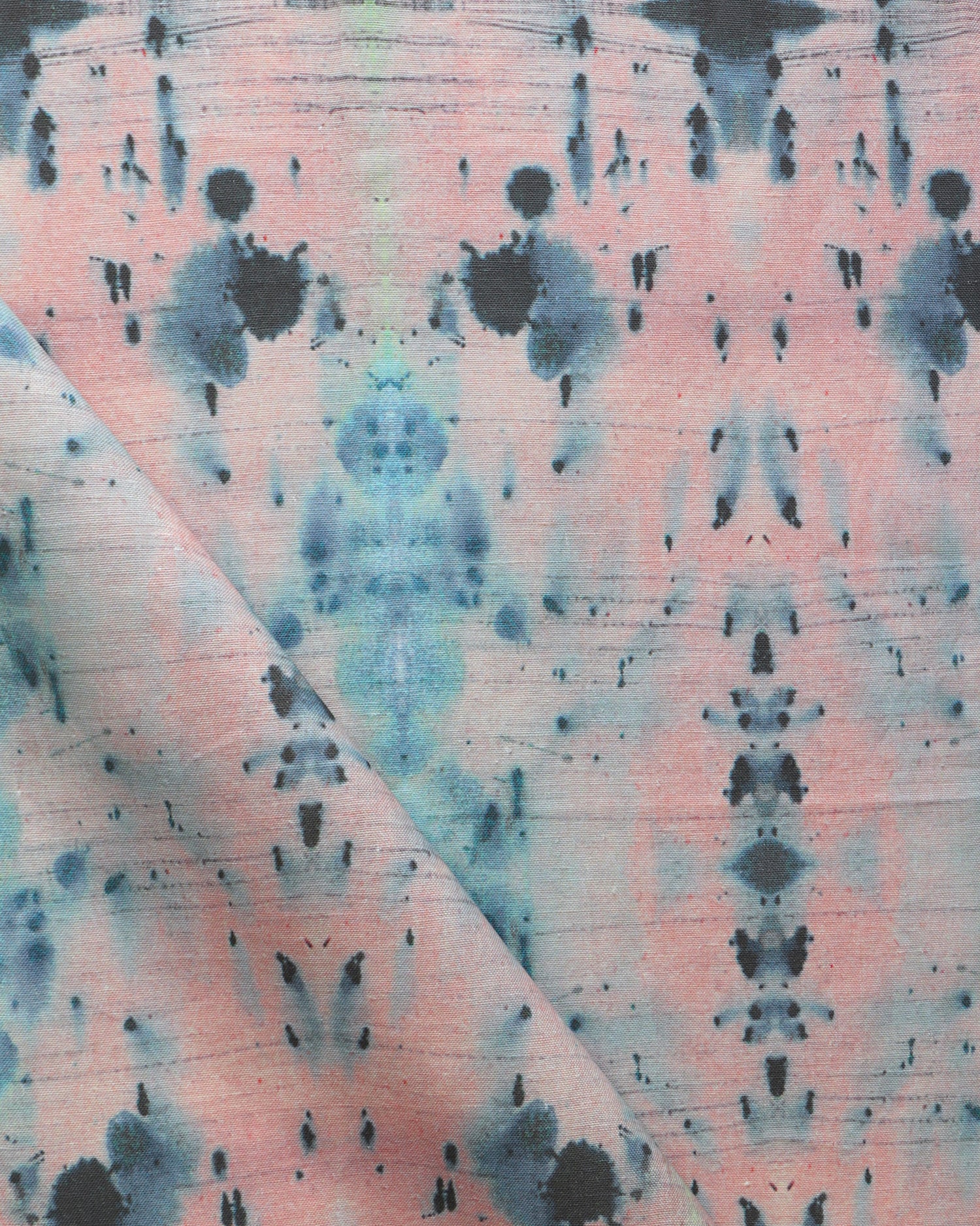 Detail of draped fabric in a watercolor ink blot print in blue and gray on a light pink field.
