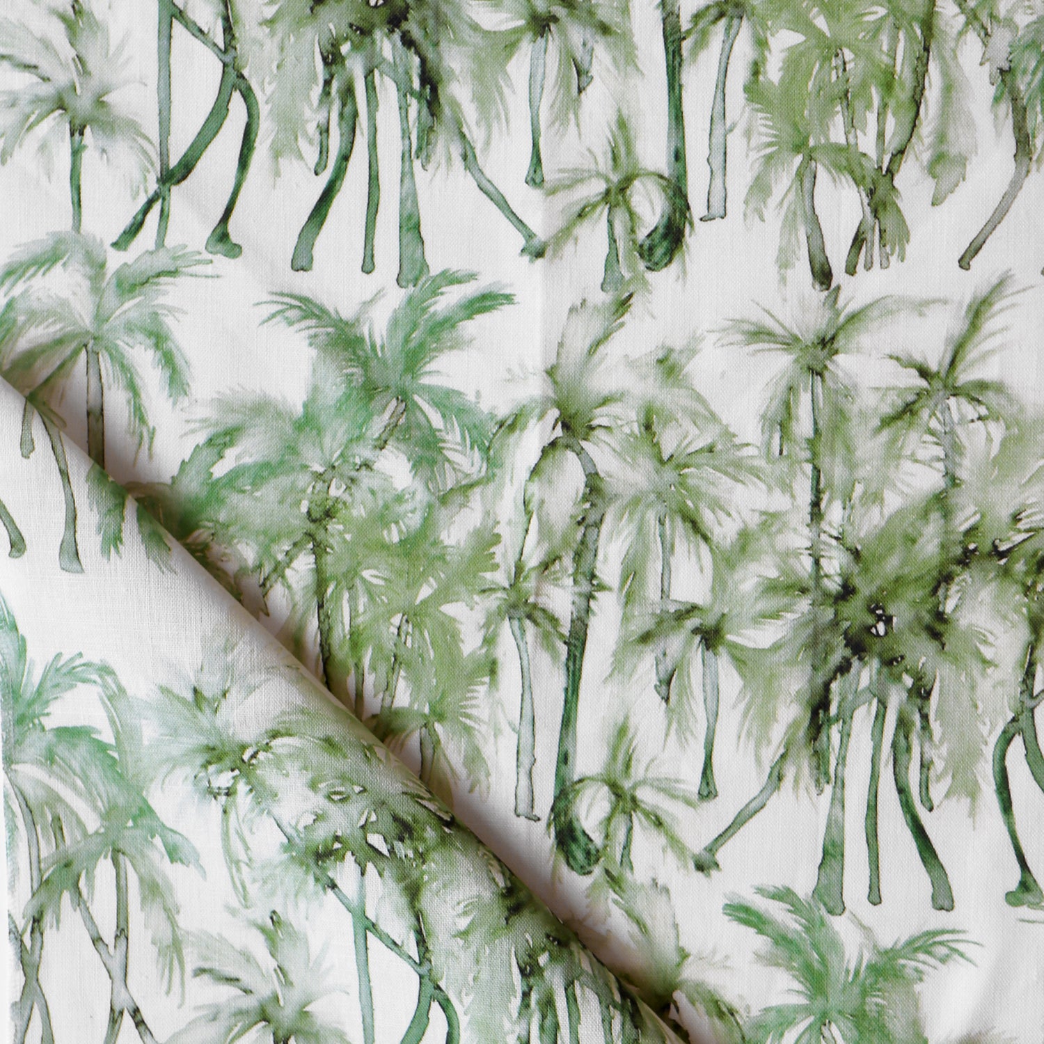 Detail of draped fabric in a painterly palm tree stripe print in shades of green on a white field.