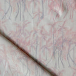 Detail of draped fabric in a painterly palm tree stripe print in shades of pink and gray on a white field.