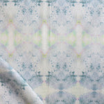 Detail of draped fabric in a watercolor ink blot pattern in shades of gray, green and pink.