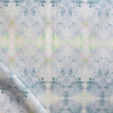 Detail of draped fabric in a watercolor ink blot pattern in shades of gray, green and pink.