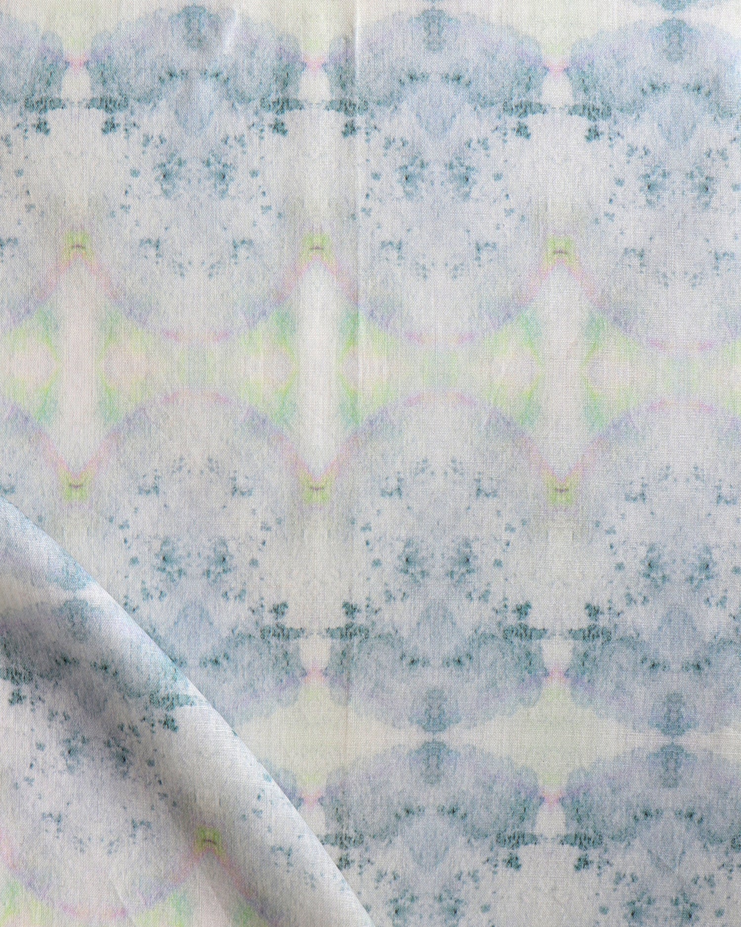 Detail of draped fabric in a watercolor ink blot pattern in shades of gray, green and pink.