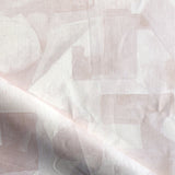 Draped fabric in a geometric puzzle piece watercolor pattern in pastel pink. 
