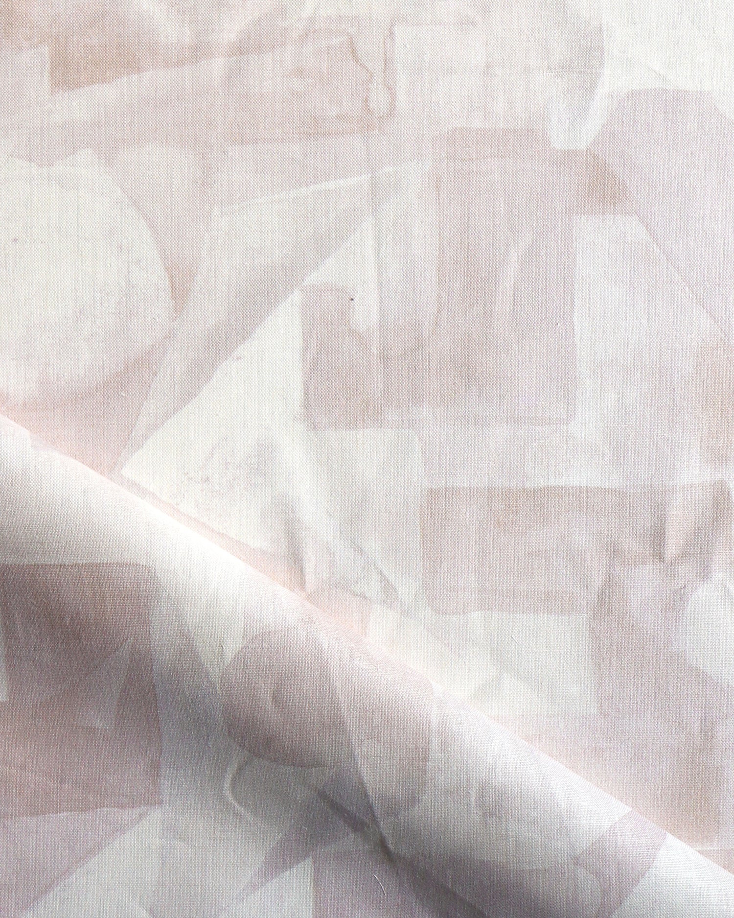 Draped fabric in a geometric puzzle piece watercolor pattern in pastel pink. 