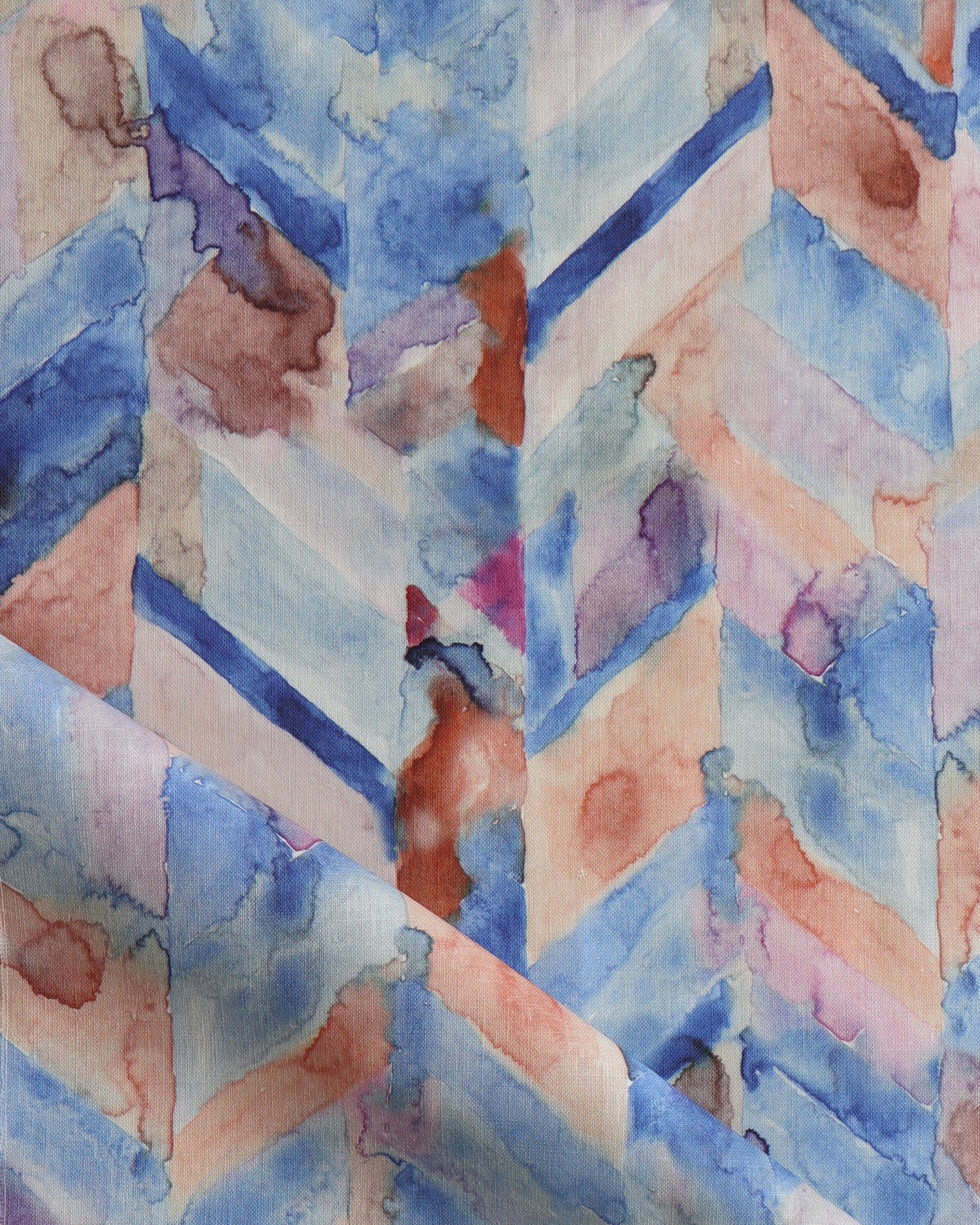 Detail of draped fabric in a painterly herringbone print in shades of blue, pink and orange.