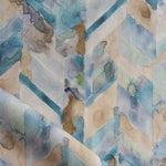 Detail of draped fabric in a painterly herringbone print in shades of blue, green and brown.
