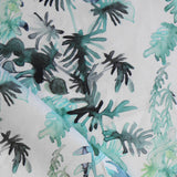 Draped fabric in an watercolor palm frond pattern in shades of teal and green. 