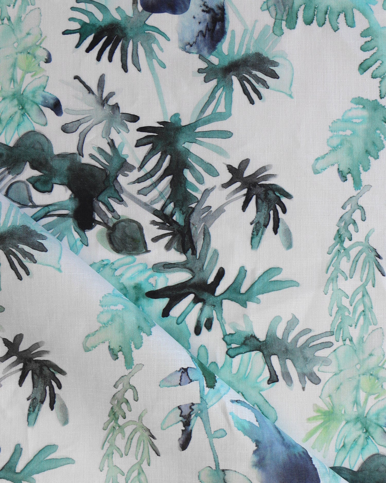 Draped fabric in an watercolor palm frond pattern in shades of teal and green. 