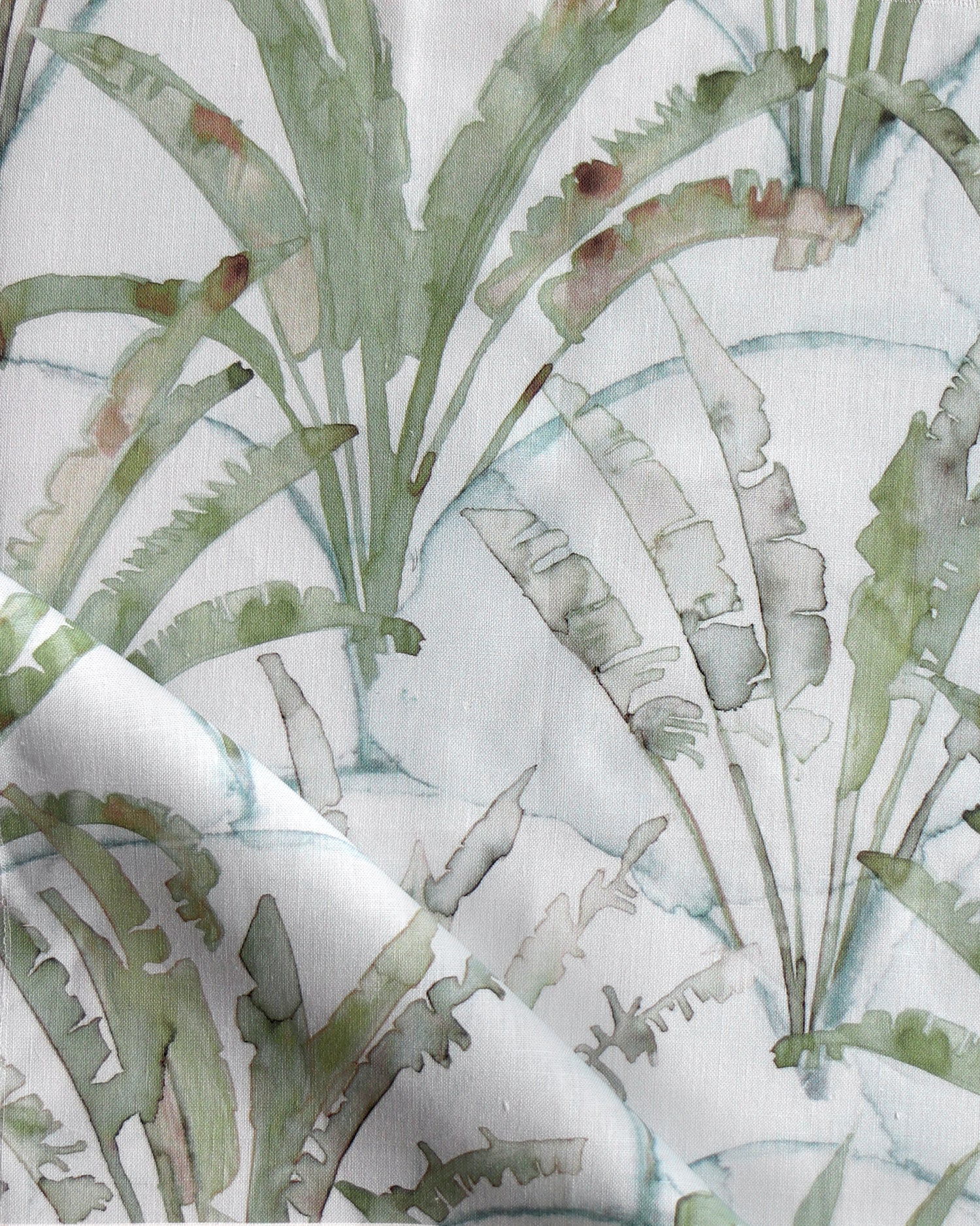 Detail of draped fabric in a painterly palm tree pattern in shades of green and brown on a blue-gray field.