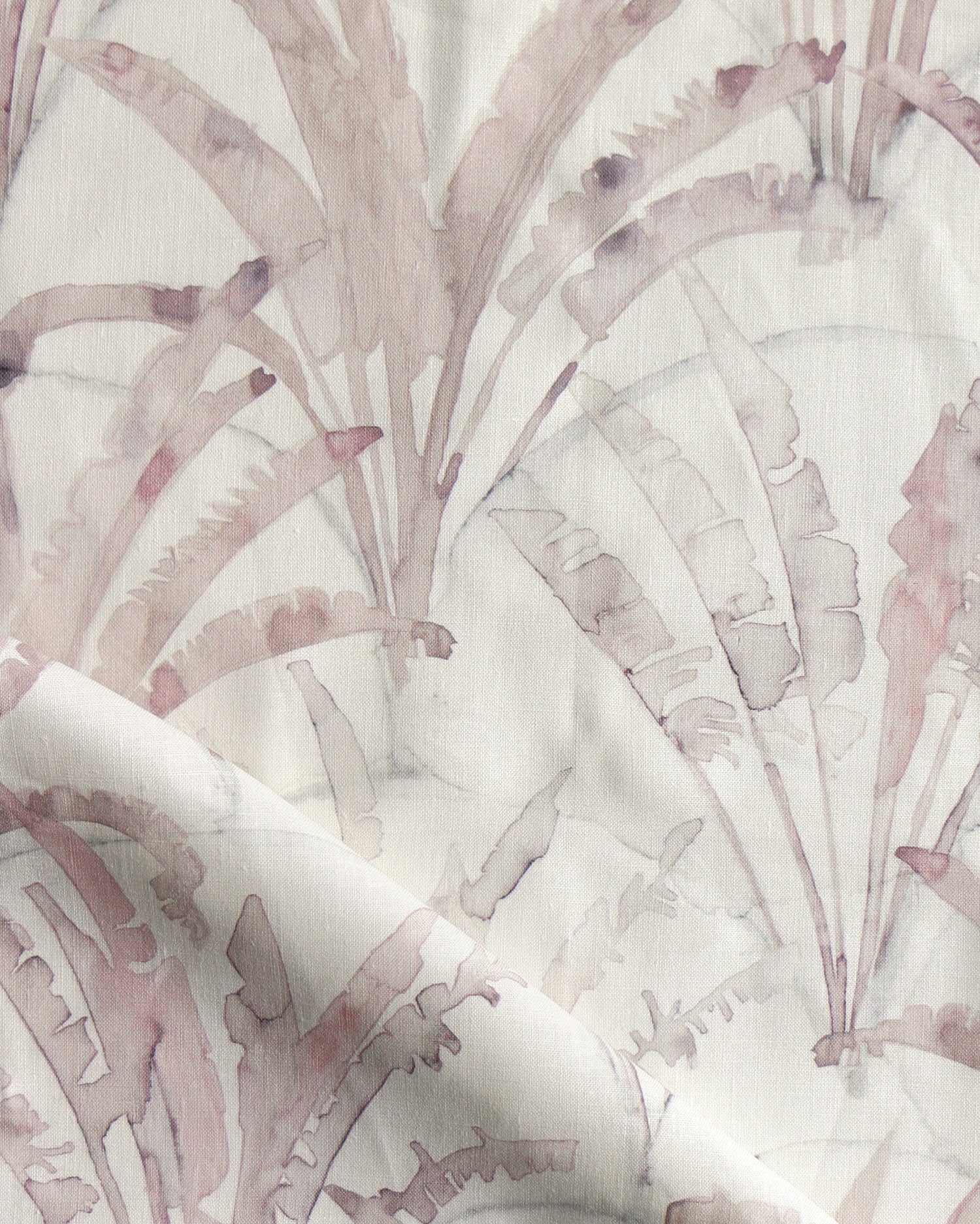 Detail of draped fabric in a painterly palm tree pattern in shades of pink and blue on a cream field.