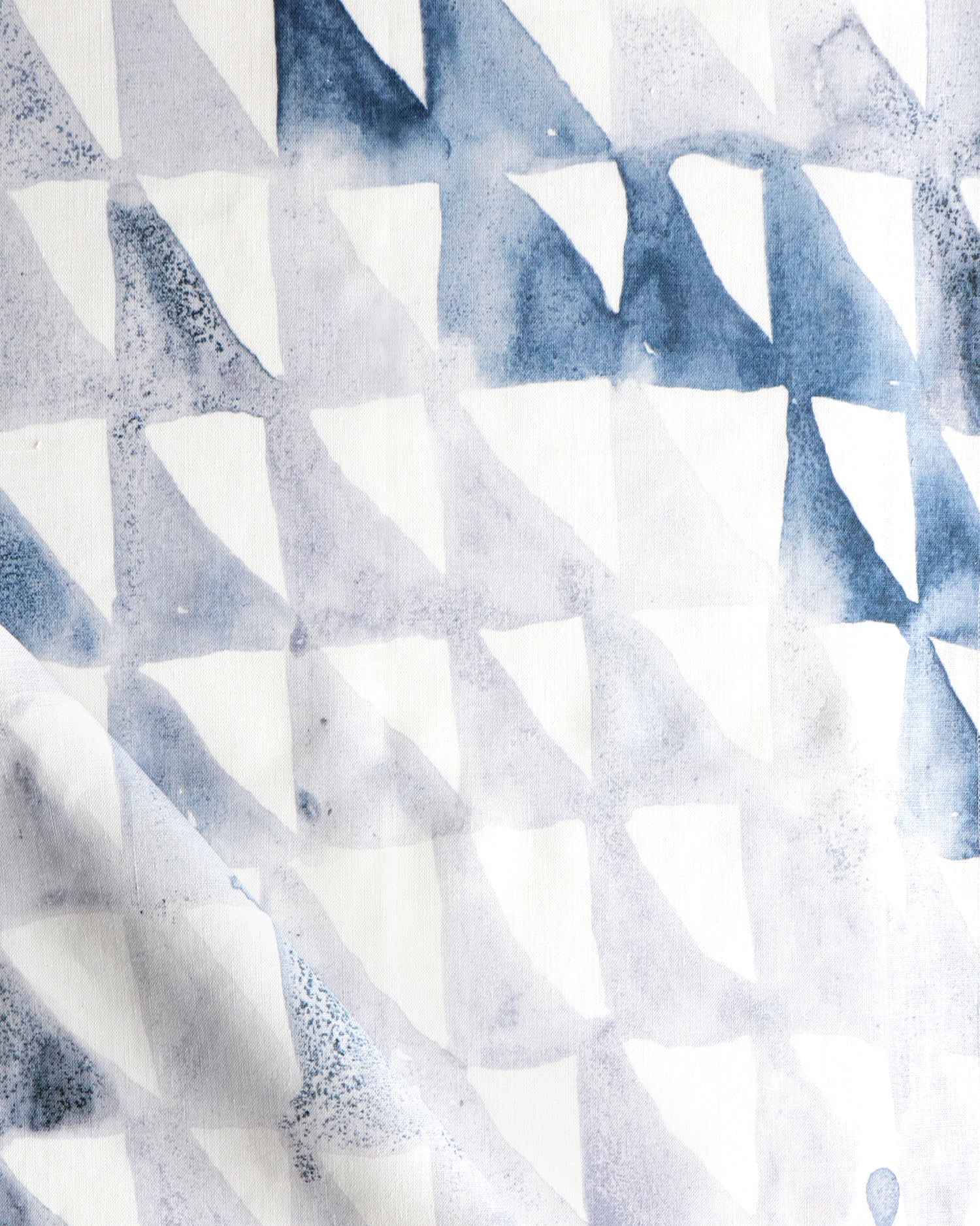 Detail of draped fabric in a painterly check pattern in shades of blue, gray and white.