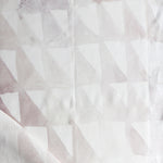 Detail of draped fabric in a painterly check pattern in shades of cream, tan and white.