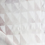Detail of draped fabric in a painterly check pattern in shades of cream, tan and white.